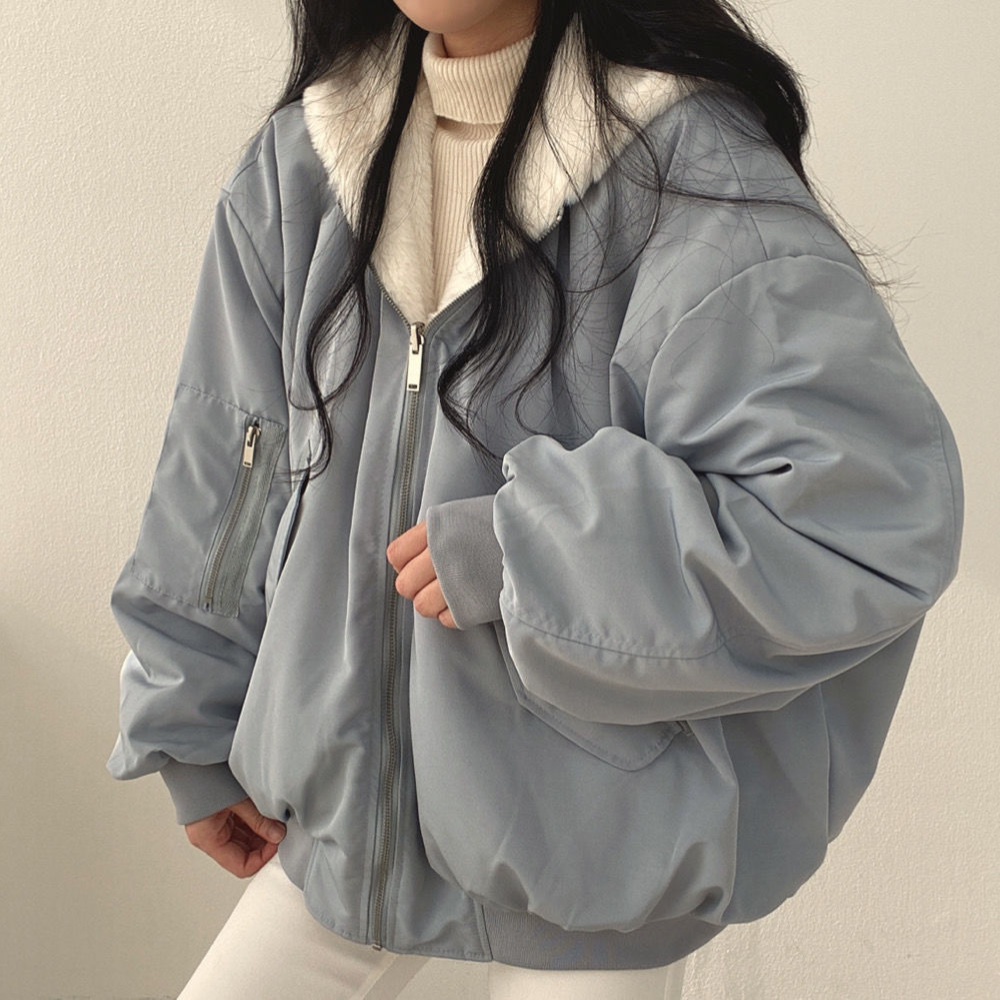 Eine Frau trägt eine blaue Wendejacke mit Kapuze, Reißverschluss und Tasche