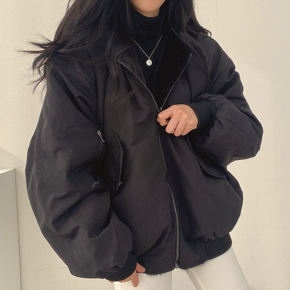 Eine schwarze Wendejacke mit Kapuze, Reißverschluss und Tasche