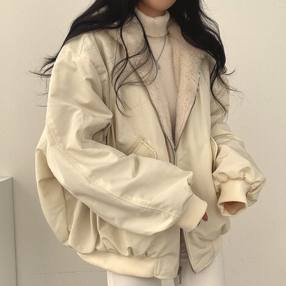 Nahaufnahme einer Frau, die eine beige Wendejacke mit Kapuze, Reißverschluss und Tasche trägt