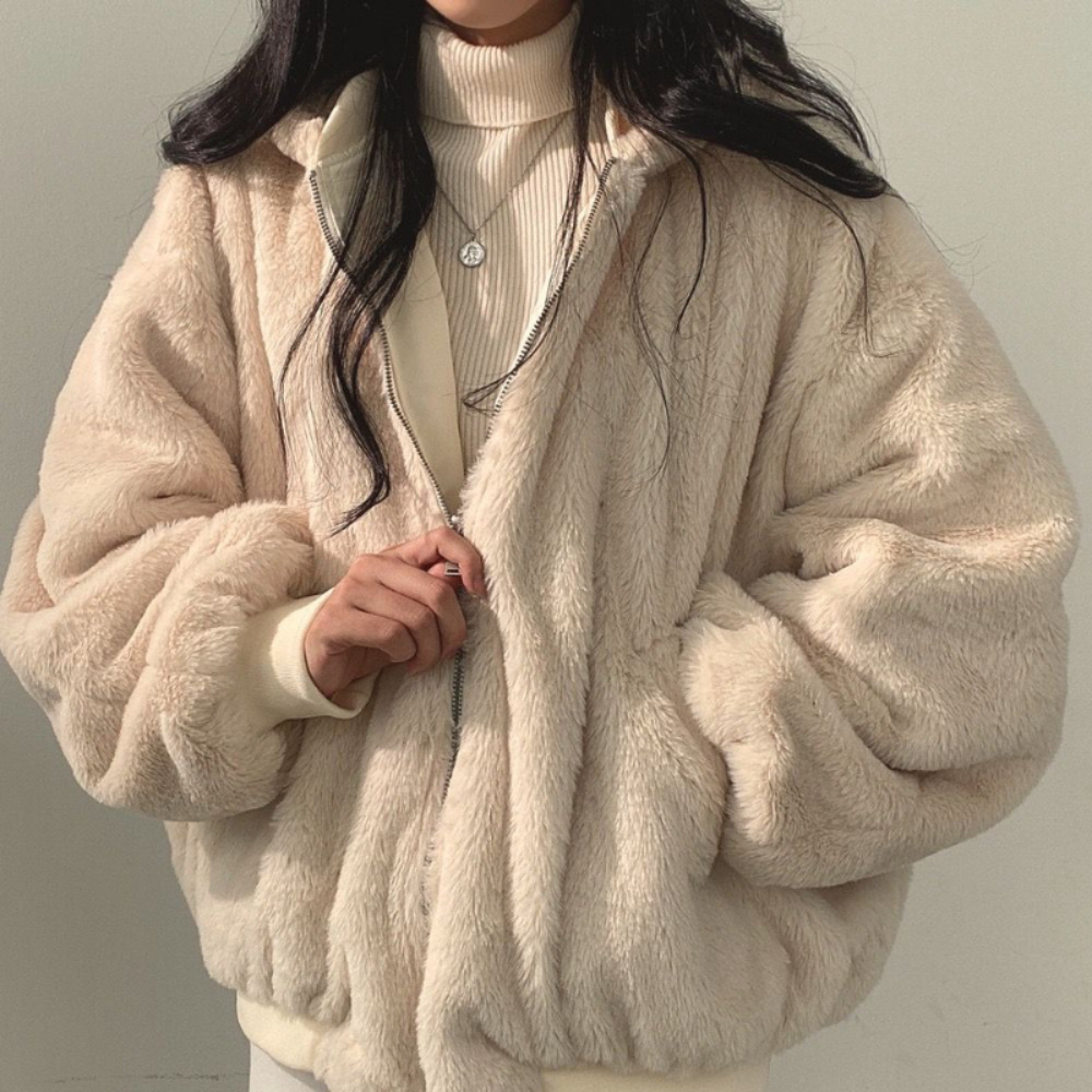 Nahaufnahme einer Frau, die eine beige Wendejacke mit Kapuze, Reißverschluss und Tasche trägt