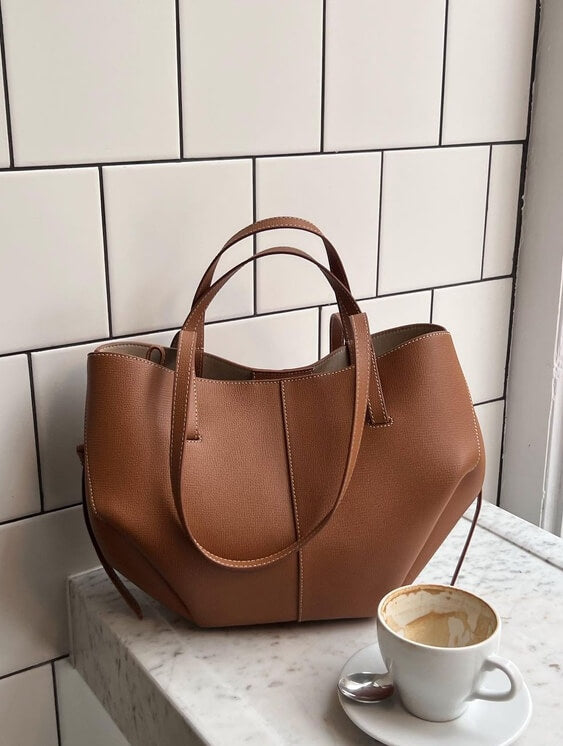 Braun ledertasche neben einer leeren kaffeetasse auf einem tisch